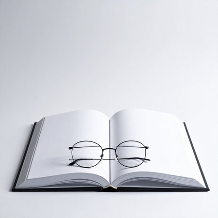 A pair of classic round eyeglasses rests on the blank pages of an open book, marking a pause in study or creative thought.の素材