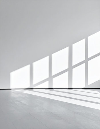 Sunlight streams through a window, casting geometric shadows across the floor and wall of a clean, empty room.の素材