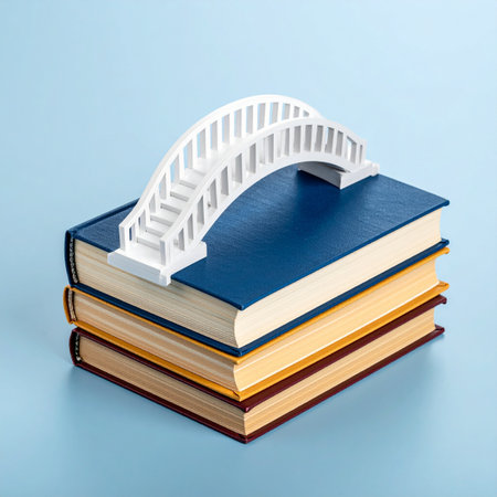 A miniature white bridge arches over a stack of colorful books, symbolizing the journey of learning and the connection between different ideas.の素材