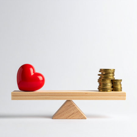 A red heart and a stack of gold coins sit in perfect equilibrium on a simple wooden scale.の素材