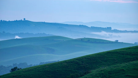 As the first light of dawn breaks, a gentle mist blankets the valleys of Tuscany's iconic rolling hills.の素材