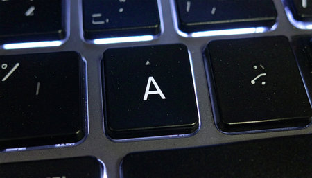 In the quiet of a dimly lit room, a single keyboard key glows with purpose.の素材