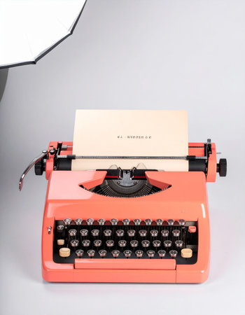 A classic orange typewriter sits ready, a blank page waiting for the next great story.の素材