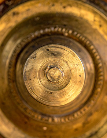 A macro view reveals the intricate details and warm patina of an antique brass object. Concentric circles draw the eye inward, telling a story of time, craftsmanship, and enduring quality.の素材