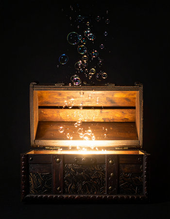 An ancient, ornate treasure chest creaks open in the darkness, revealing not gold or jewels, but a brilliant, magical light.の素材
