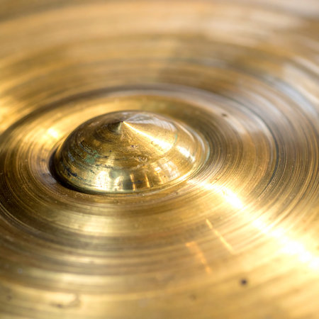 A macro photograph captures the intricate details of a golden brass cymbal.の素材
