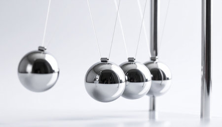 A single steel ball is frozen in motion, about to strike a line of identical spheres.の素材