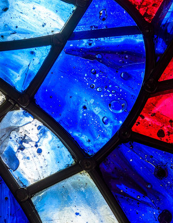 Sunlight streams through an ancient stained glass window, illuminating the deep cobalt and azure blues.の素材
