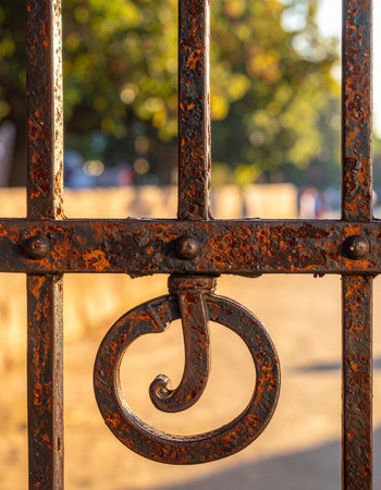 A close-up view captures the rich, textured rust on an antique wrought iron gate latch, glowing in the warm, golden light of a late afternoon.の素材