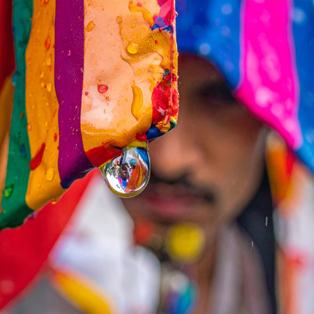 A single droplet clings to a canvas of vibrant, dripping colors, perfectly reflecting the world around it.の素材