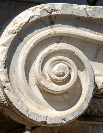 A detailed close-up captures the weathered texture of an ancient stone spiral, part of a classical column's capital.の素材