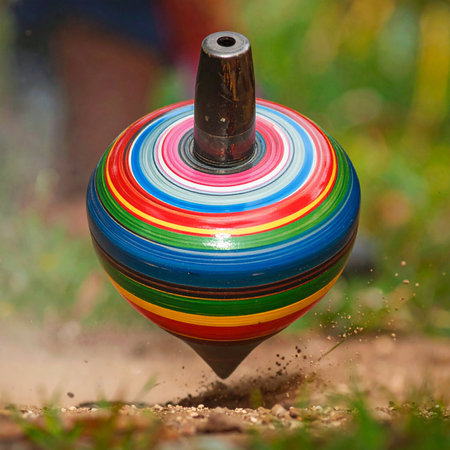 A classic wooden spinning top, painted with vibrant rainbow stripes, whirls with incredible speed on the dusty ground.の素材