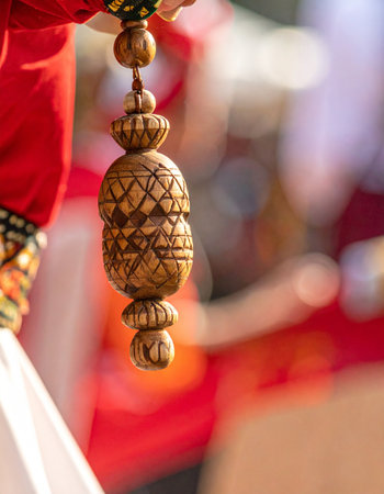 A close-up captures the exquisite detail of a hand-carved wooden tassel, a key element of a traditional folk dancer's costume.の素材