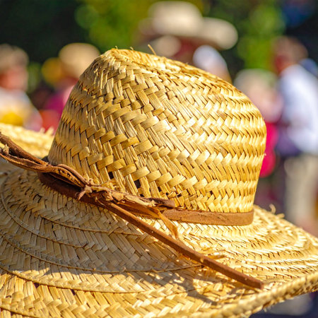 A close-up view of a beautifully woven straw hat resting in the bright summer sun.の素材