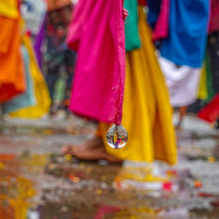A crystal orb hangs amidst a whirlwind of vibrant festival colors, capturing an upside-down world of celebration within its tiny sphere.の素材