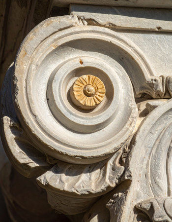 A close-up view captures the intricate craftsmanship of a classical volute on a stone column capital.の素材