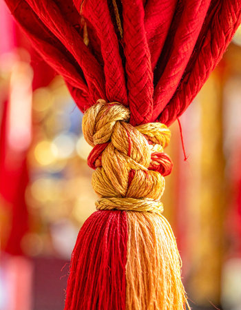 A close-up shot captures the intricate details of a luxurious red and gold tassel.の素材