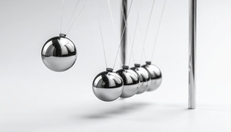 A single steel sphere is frozen in mid-air, poised to strike a line of its counterparts.の素材