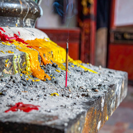 A single stick of incense smolders peacefully, its fragrant smoke curling upwards as a quiet offering.の素材