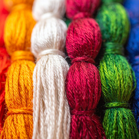 A vibrant collection of handmade yarn tassels stands in a colorful row, showcasing a spectrum of rich hues.の素材