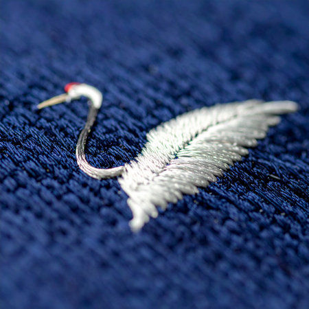 A close-up macro shot captures the exquisite detail of a silver and white crane embroidered onto a rich, textured blue fabric.の素材