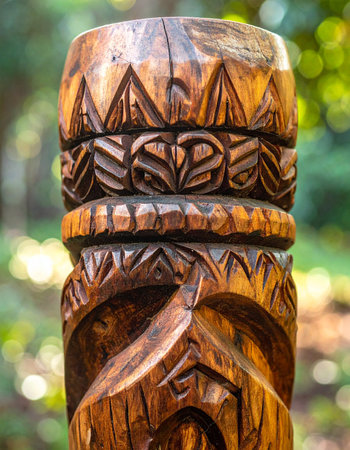 A close-up view captures the intricate details and rich textures of a hand-carved wooden tiki pole.の素材