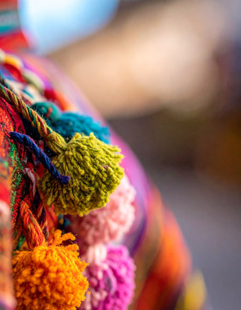 A macro view captures the intricate detail and vibrant colors of handmade yarn tassels on a traditional woven textile.の素材
