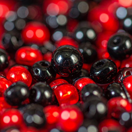 A single black bead stands in sharp focus amidst a vibrant, chaotic collection of red and black spheres.の素材
