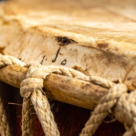 The weathered skin and tightly woven ropes of a traditional hand drum tell a story of rhythm and culture.の素材