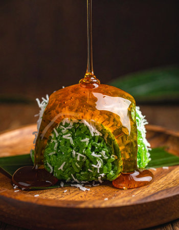 A decadent stream of golden palm sugar syrup cascades over a freshly steamed Kue Putu, a traditional Southeast Asian delicacy.の素材