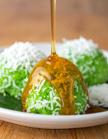 A delicious drizzle of warm Gula Melaka, or palm sugar syrup, cascades over a freshly made Klepon.の素材