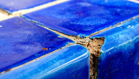 A macro perspective reveals the intricate decay of vibrant blue ceramic tiles. The crumbling grout and deep cracks tell a story of time and neglect, highlighting the need for repair and renovation.の素材
