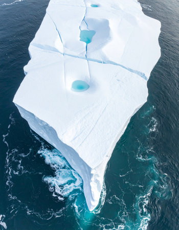From high above, a colossal iceberg drifts silently through the frigid arctic ocean.の素材
