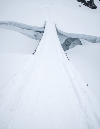 A breathtaking high-angle view captures the perilous beauty of a deep crevasse splitting a vast snowfield.の素材