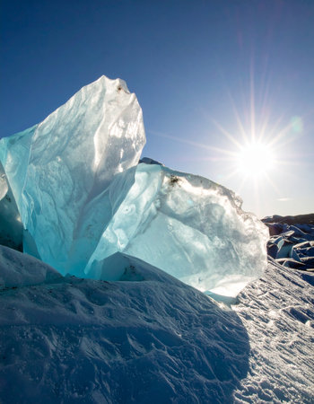 Bathed in the brilliant light of a low-hanging sun, massive blocks of pure, turquoise ice stand like natural sculptures on a frozen expanse.の素材
