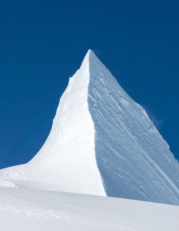 A breathtaking view of a sharp, snow-covered mountain peak piercing a flawless, deep blue sky.の素材
