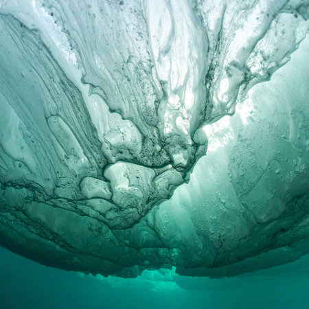 From the silent depths, a breathtaking view upwards reveals the intricate, sculpted underside of a massive iceberg.の素材