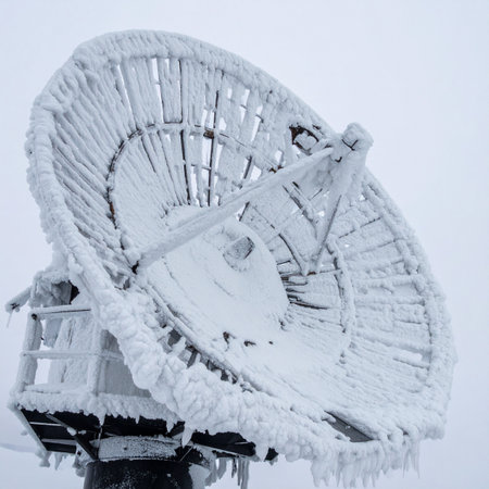 satellite dish covered with snow in winter, closeup of photoの素材