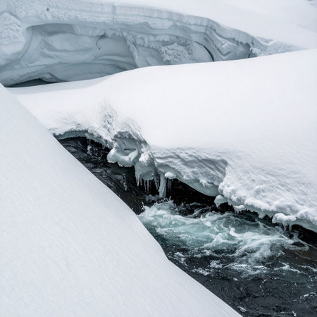 A powerful stream of meltwater carves its path through a deep, pristine snowpack.の素材