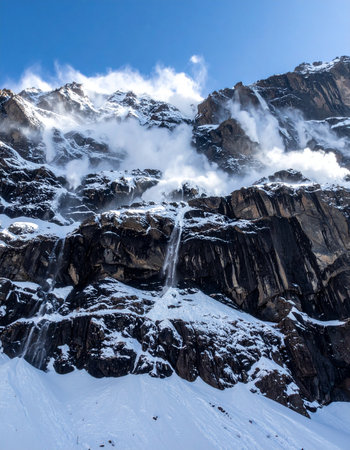Witness the raw, untamed power of nature as a massive avalanche thunders down a steep, rocky mountain face.の素材