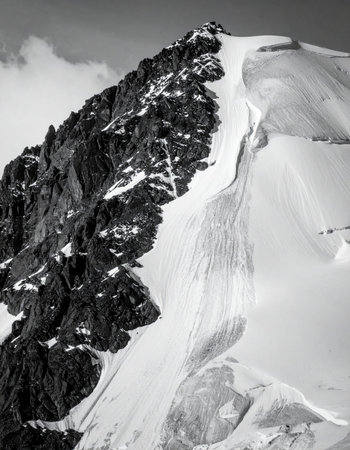 A stark, high-contrast black and white photograph capturing the raw power of the alps. A sharp, rocky arの素材