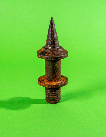 A close-up of a single, heavily rusted iron finial, once part of an old fence or gate. Its weathered texture and sharp point tell a story of age, decay, and forgotten boundaries.の素材