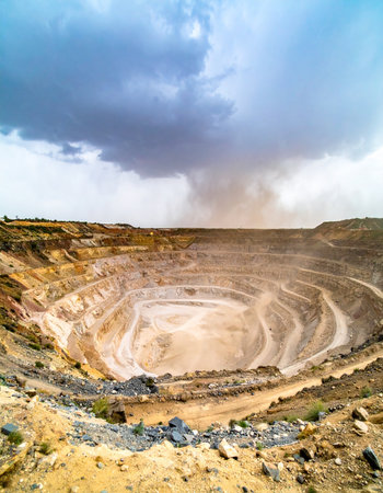 A vast open-cast mine carves into the earth, its terraced levels creating a man-made canyon.の素材