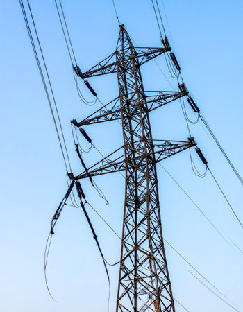A towering steel lattice pylon stands sentinel against a vast, clear blue sky, its network of high-voltage cables carrying the essential energy that powers cities and industries.の素材