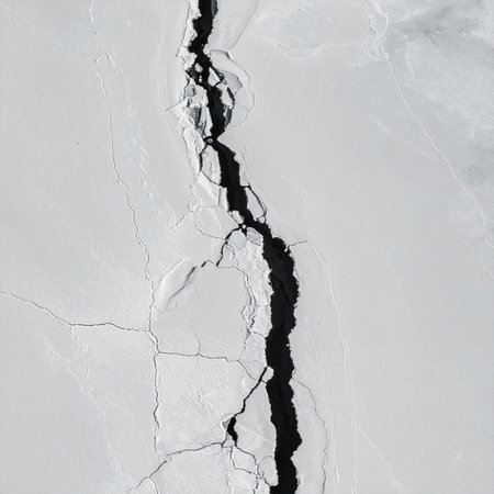 A stark, high-contrast view of a deep fissure breaking through a solid white surface.の素材