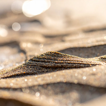 A close-up, selective focus shot captures the intricate layers of golden sand grains, shimmering under soft, warm sunlight.の素材