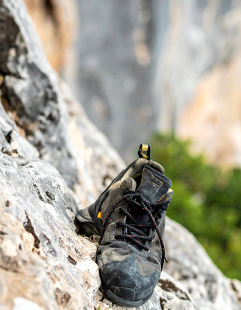 A close-up captures the intense detail of a well-used climbing shoe, its rubber sole gripping the textured surface of a sheer rock face. Each scuff and layer of chalk dust tells a story of perseverance, challenge, and the relentless pursuit of the summit, symbolizing the grit and determination required in outdoor adventure sports.の素材