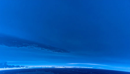 From the edge of space, the delicate, glowing curve of Earths atmosphere separates the deep blue planet from the infinite void. A serene and awe-inspiring perspective on our world, evoking feelings of wonder, exploration, and the vastness of the cosmos.の素材