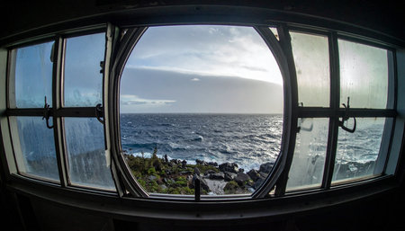 From the quiet solitude of a room, a wide, curved window frames a dramatic view of the vast ocean. The setting sun reflects off the choppy waves, creating a scene of both powerful nature and peaceful contemplation. Its a moment of introspection, looking out at the endless horizon and the possibilities it holds.の素材