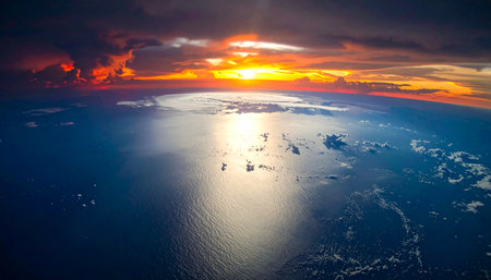 From a breathtaking orbital vantage point, the sun dips below the Earths curve, setting the atmosphere ablaze with fiery colors. Its golden light stretches across the vast ocean, offering a serene, powerful perspective on the beauty of our world.の素材